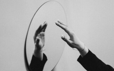 Zwart-witbeeld van handen die naar hun spiegelbeeld reiken